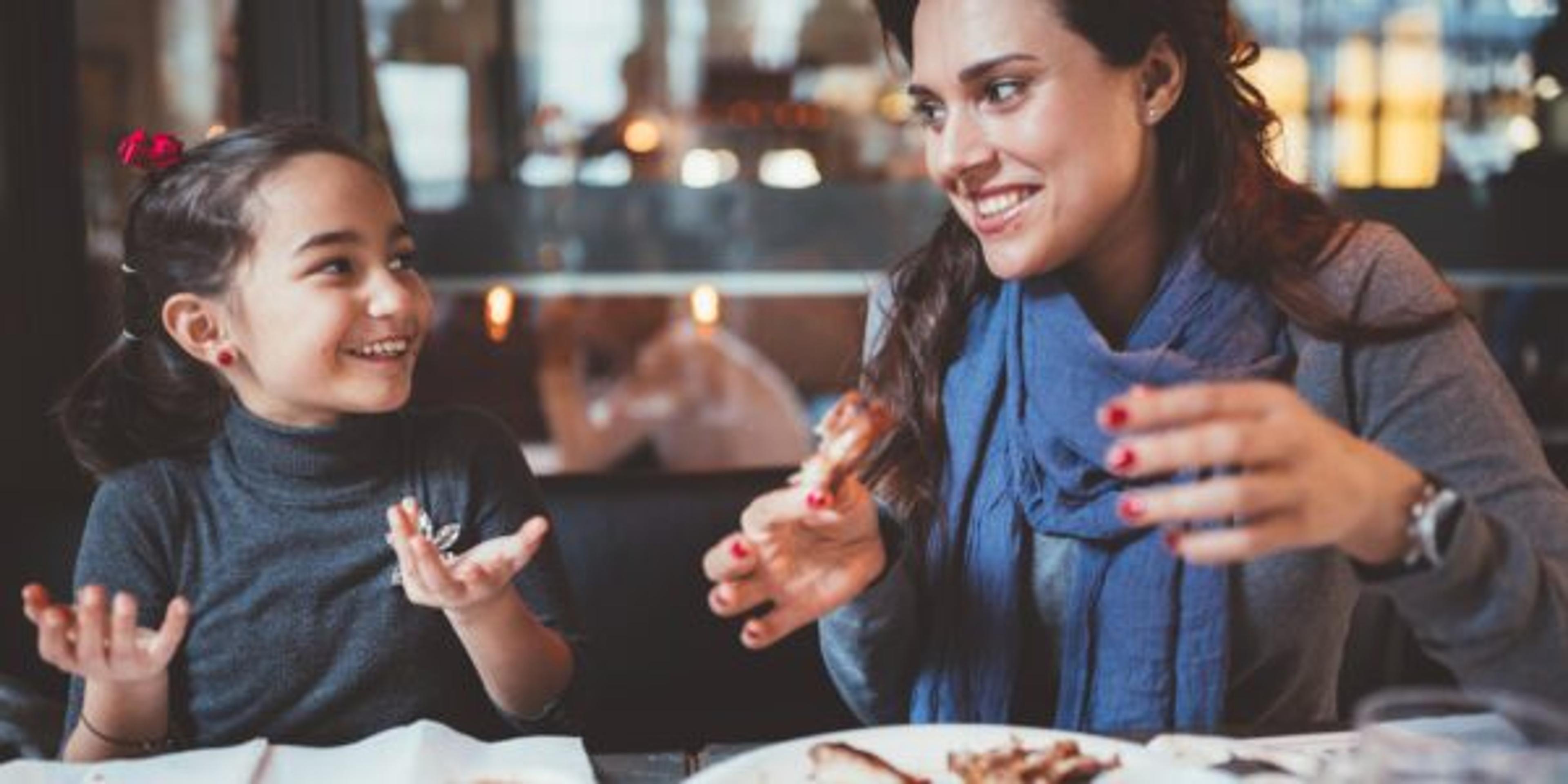 A mother and daughter enjoy a meal of chicken wings together.