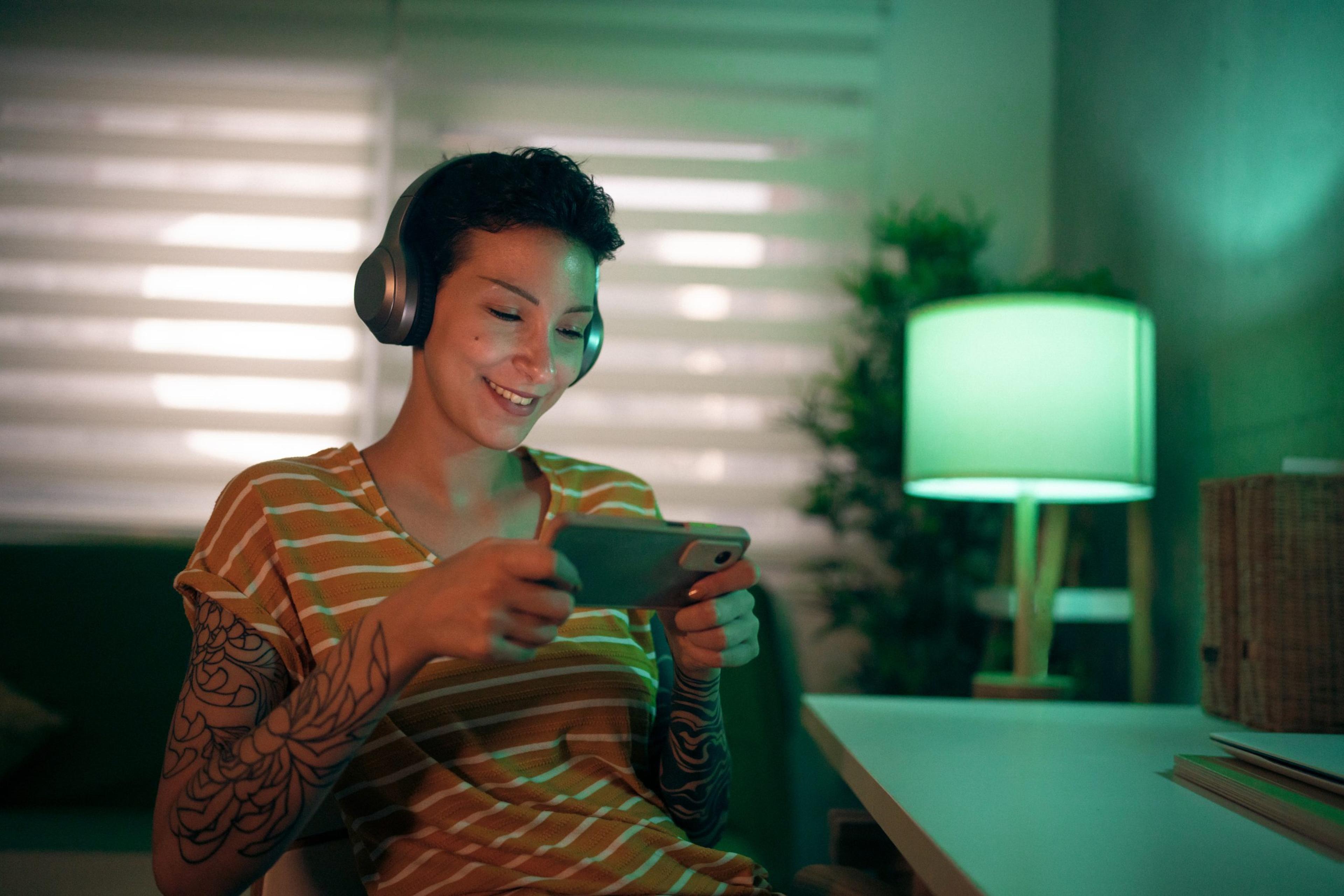 Modern Caucasian young woman playing video games on mobile phone
