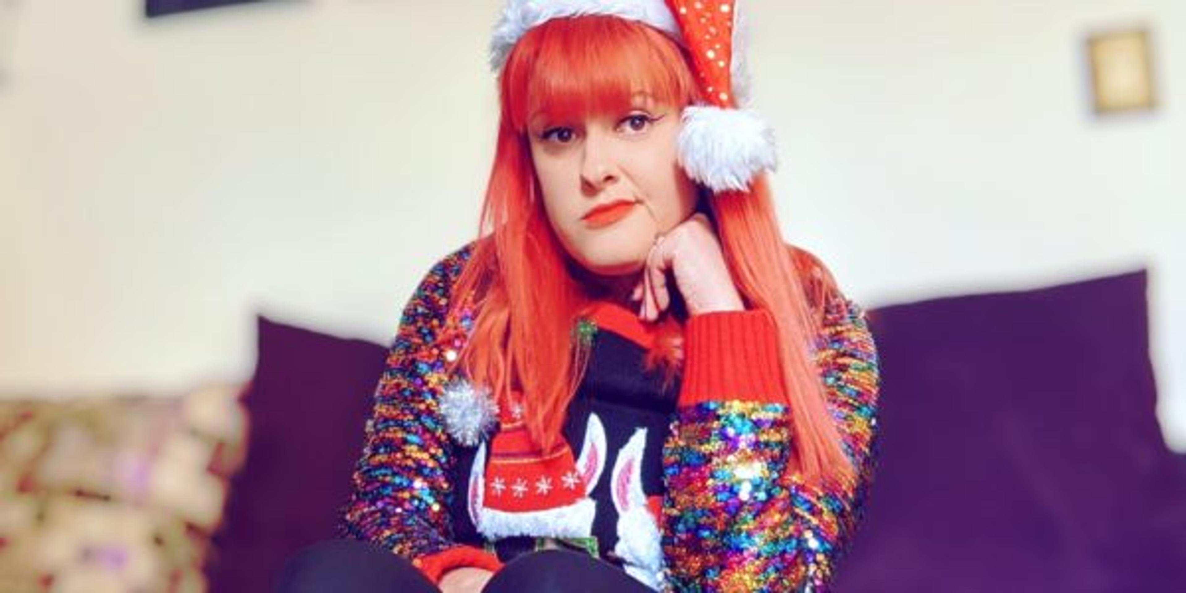 woman poses in a Santa hat while feeling sad with the holiday blues
